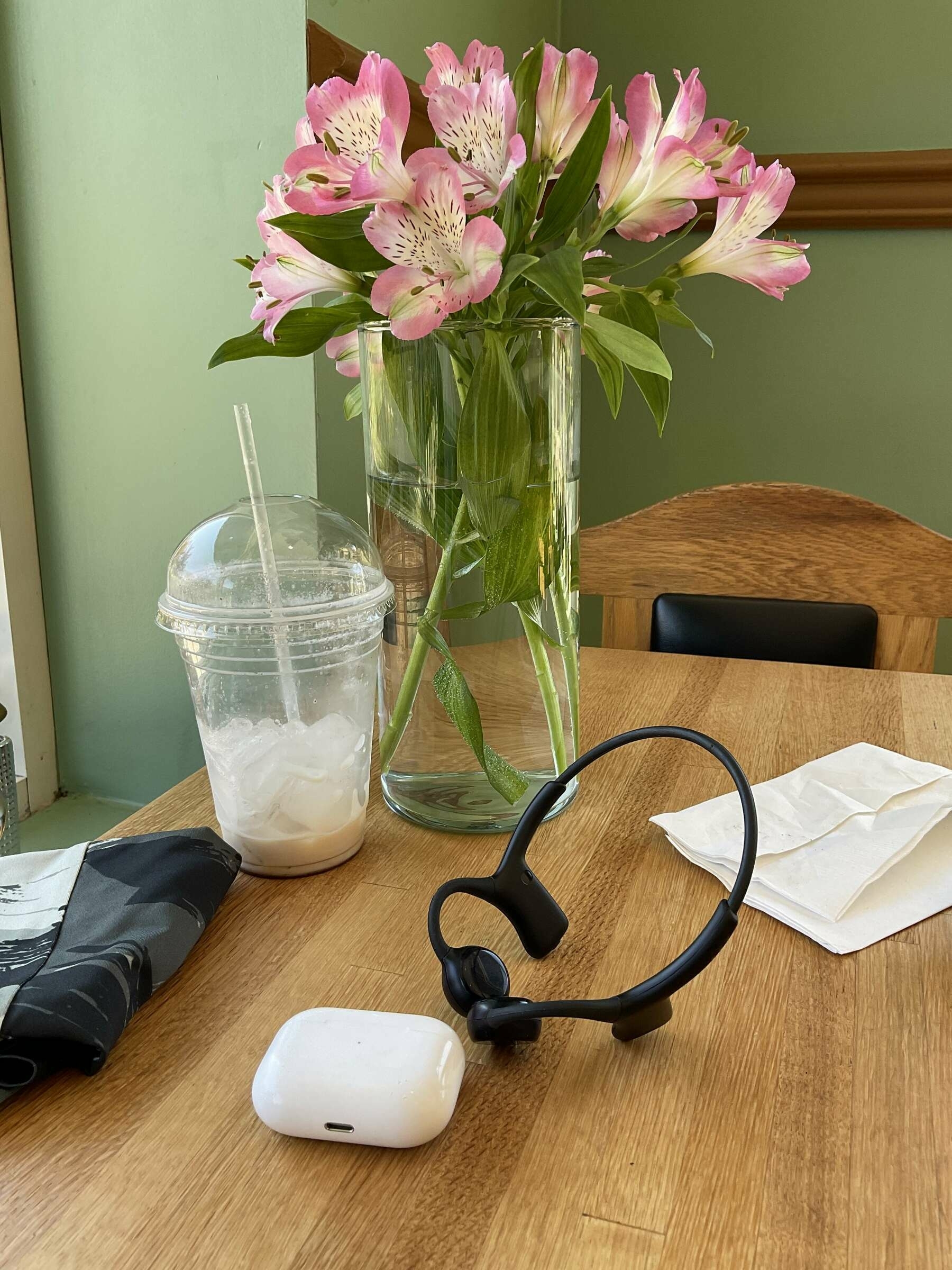 Sentien Audio and Apple AirPods Pro on table in front of vase with flowers sitting in water